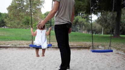 Un hombre juega con una niña en un columpio en Valencia. 