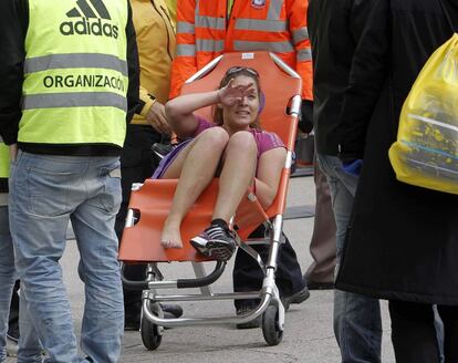 Las asistencias sanitarias auxilian a una corrredora agotada tras su llegada a la meta de la maraton de Madrid , en la se han inscrito 26.000 corredores.