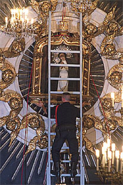 Un bombero baja del altar la Virgen de la Paloma, de Madrid.