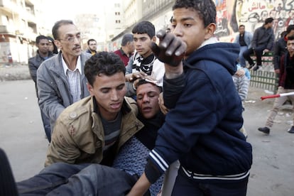 Unas personas transportan a un herido durante los enfrentamientos de manifestantes contra la policía en el segundo aniversario de la revolución egipcia en la plaza de Tahrir del Cairo.