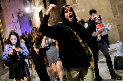 Jóvenes sin mascarilla celebran, en una calle del barrio del Born (Barcelona), el fin del estado de alarma.