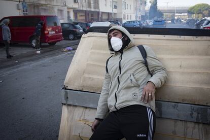 Un hombre se protege tras un contenedor de las cargas policiales y los gases lacrimógenos.