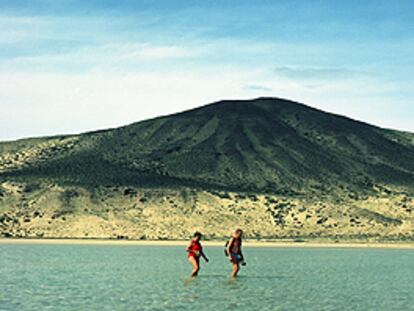 Una pareja cruza una laguna natural que la marea suele formar en la playa de sotavento de la península de Jandía, en Fuerteventura.