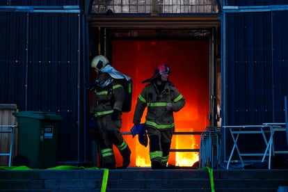 Varios bomberos salen por la entrada principal de la Bolsa de Copenhague, este martes durante el incendio. 