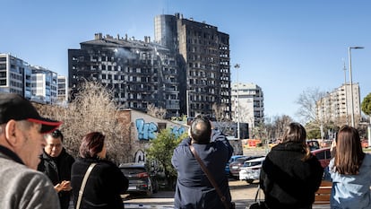 Un grupo de personas mira el edificio incendiado, este viernes.