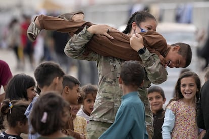 Una soldado estadounidense juega con niños afganos recientemente evacuados en la base aérea estadounidense de Ramstein, Alemania.