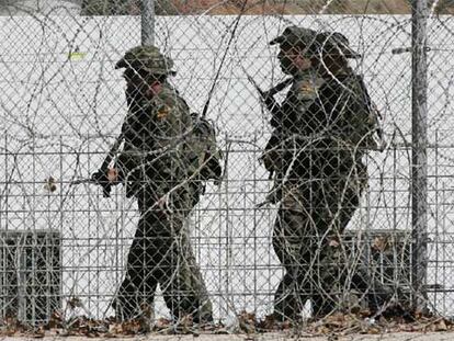 Tres legionarios pasan ante una garita junto a la valla fronteriza de Ceuta.