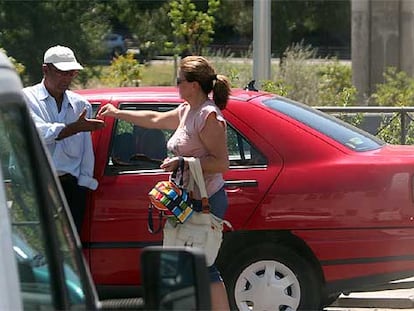 Una mujer entrega unas monedas a un <b><i>gorrilla</b></i> en la calle San Lorenzo, junto al hospital Ramón y Cajal.