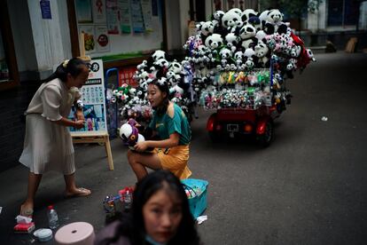 Una vendedora clasifica muñecos de peluche en una calle de Chengdu (China).