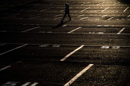 Una persona camina por un estacionamiento vacío al atardecer en Turín (Italia).