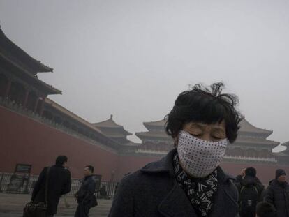 Una mujer lleva una mascara protectora contra la contaminación mientras visita la Ciudad Prohibida de Pekín, en China.