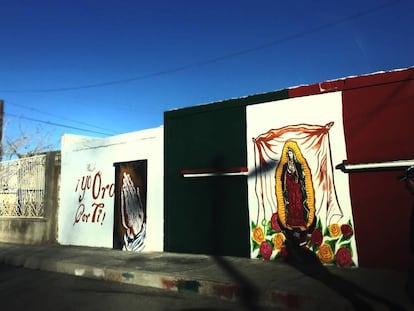 Um mural com imagem da virgem de Guadalupe sobre a bandeira mexicana em Ciudad Juárez.