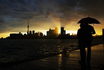 Una pareja mira el horizonte y la puesta de sol en Toronto tras una fuerte tormenta.