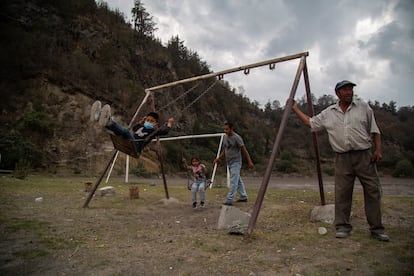 Francisco Castro (i) juega con sus hijos junto a Lázaro Chalché (d) a un costado de la ladera del volcán Popocatépetl en Xalitzintla.