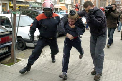 Dos "ertzainas" llevan detenido a uno de los participantes de la manifestación.