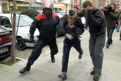 Dos "ertzainas" llevan detenido a uno de los participantes de la manifestación.