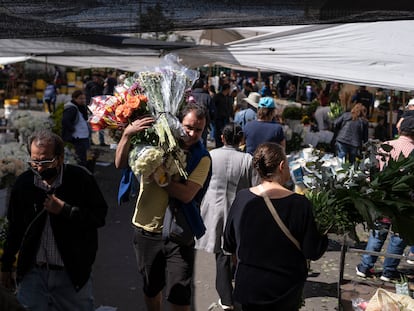 Un hombre carga ramos de flores en el mercado de la plaza Paloquemao, en Bogotá (Colombia), el 13 de febrero de 2024.