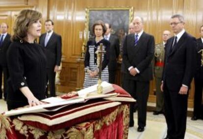 Soraya Sáenz de Santamaría takes the pledge in front of King Juan Carlos and Queen Sofía, with Alberto Ruiz-Gallardón looking on.