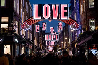 Shoppers walk beneath the Christmas festive lights on Carnaby Street in London on November 25, 2016, one month before Christmas Day. / AFP PHOTO / Justin TALLIS