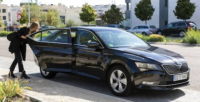 Una mujer abre la puerta de un coche VTC de Cabify.