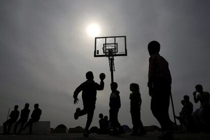 Un grupo de niños juega al baloncesto en el campamento para refugiados del puerto del Pireo en Grecia.