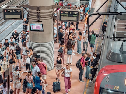 Viajeros junto a un tren de Cercanas en la estacin madrile?a de Atocha.