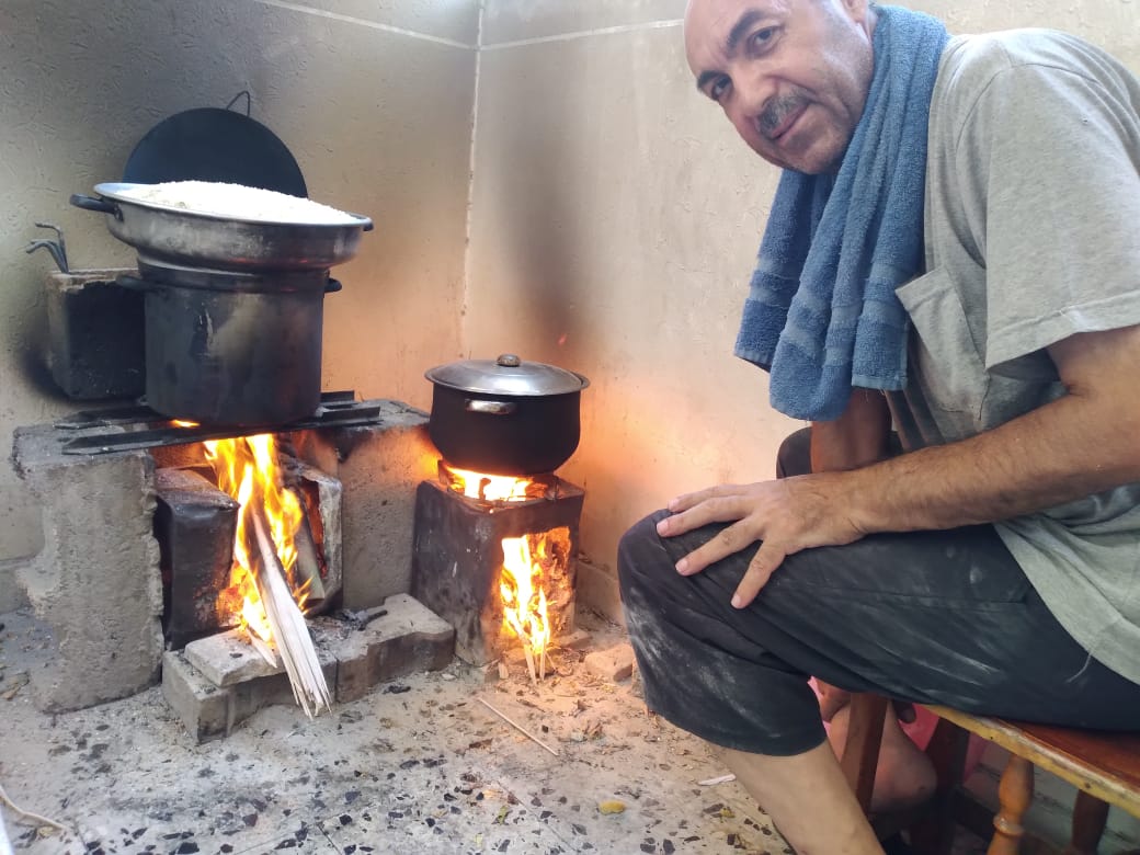 Nasser Rabah calentando la comida de forma rudimentaria en su casa de Al Maghazi, en el centro de Gaza.