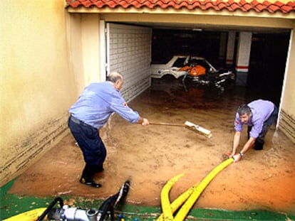 Dos bomberos extraían ayer con una bomba de achique el agua de un aparcamiento inundado en Segur de Calafell.