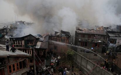 Bomberos luchan para extinguir las llamas de un incendio declarado en una zona residencial en Srinagar, capital estival de la Cachemira india.