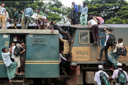 Pasajeros de Bangladesh intentan escalar hasta el techo de un tren atestado en una estación de ferrocarril en Dhaka, Bangladesh.