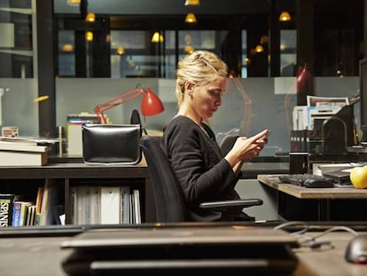 Una mujer consulta su teléfono en el trabajo.