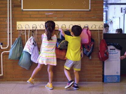 Dos niños hacen cuelgan sus mochilas en la Escola Catalonia de Barcelona. 