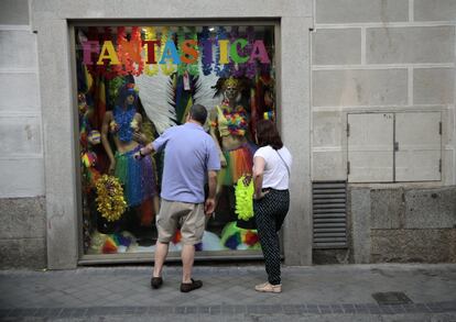 Unos transeúntes miran el escaparate de una tienda de complementos para el World Pride.