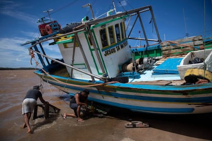 Los pescadores arreglan una barca en la playa.