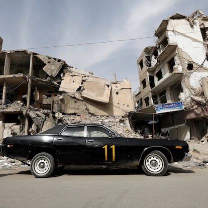 A woman walks past a vehicle parked near damaged buildings in Douma, in the eastern suburbs of Damascus, Syria March 9, 2021. Picture taken March 9, 2021. REUTERS/Omar Sanadiki TPX IMAGES OF THE DAY
