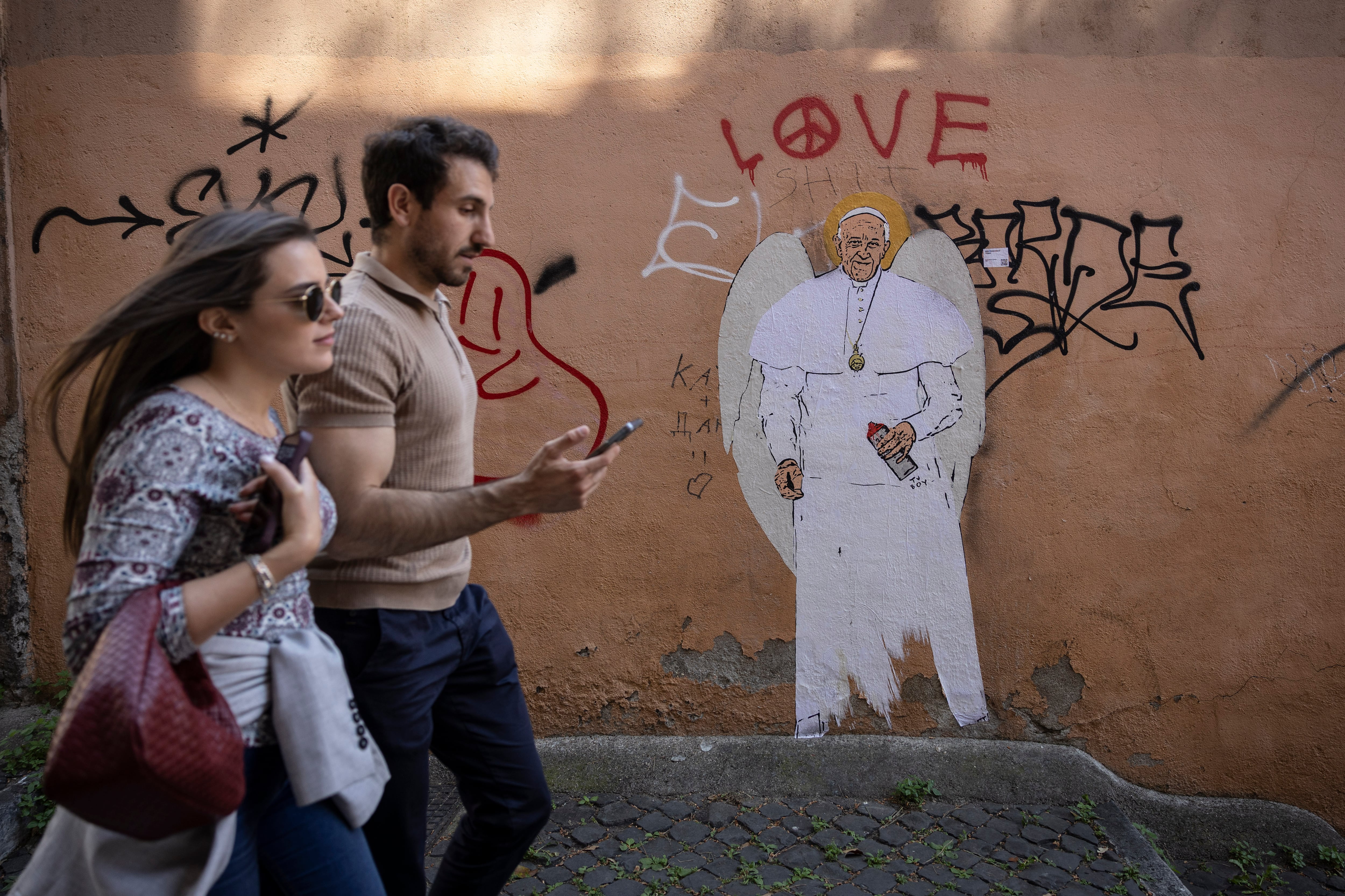 Una pareja pasea delante de un mural de Papa Francisco en las inmediaciones del Vaticano.    