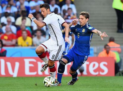 Mesut Özil de Alemania y Lucas Biglia de Argentina compiten por el balón.