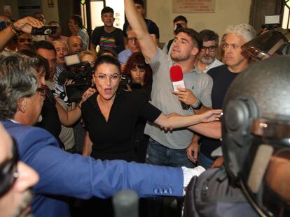 La exdiputada de Andalucía Macarena Olona (en el centro de la imagen) intenta acceder al paraninfo de la Facultad de Derecho de Granada este jueves, rodeada de manifestantes y de agentes antidisturbios.