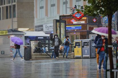Transeúntes pasean por el centro de Madrid en una jornada marcada por las lluvias y la bajada de temperaturas.