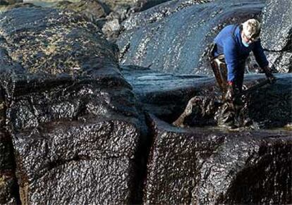 Un hombre realiza labores de limpieza entre las rocas de la costa de Muxía.