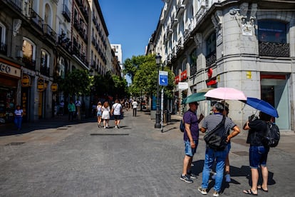 Varias personas se protegen del calor con paraguas en Puerta del Sol, hoy en Madrid.
