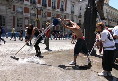 Participantes en el Movimiento 15-M durante la limpieza ayer de la Puerta del Sol.