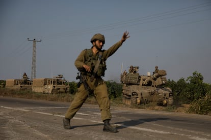 Un soldado israelí da instrucciones a los vehículos blindados que se dirigen hacia la frontera sur con la franja de Gaza.