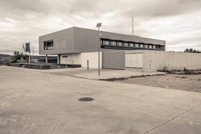 “El edificio de la comisaría era un cubo flamante de dos pisos, de grandes paredes grises interrumpidas por grandes ventanales, que se levantaba en medio de un descampado, ya en el extrarradio de Gandesa”.