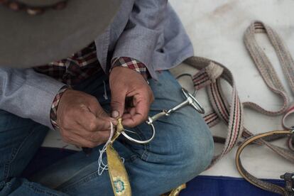 Un jinete tibetano cose una cinta para el arnés de su caballo, en la meseta del Tíbet, en el condado de Yushu (China).