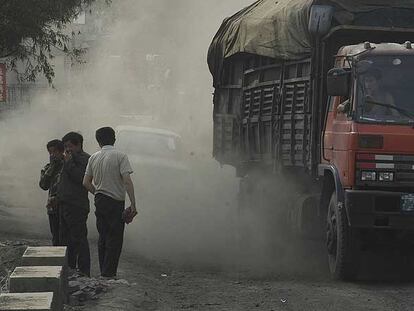Varios transeúntes cubren sus rostros al paso de un camión cargado de carbón, ayer en el norte de China.