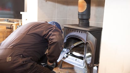 Un hombre pasando el aspirador dentro de la chimenea.