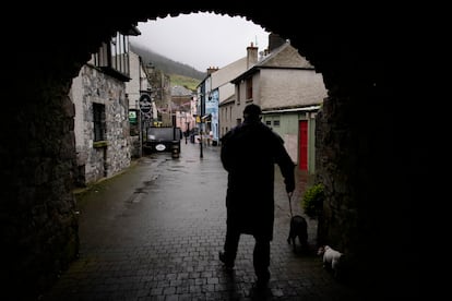 A man takes his dogs for a walk in the rain on a street in Carlingford, Ireland, Tuesday, April 11, 2023