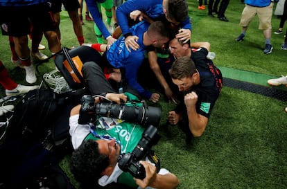 El goleador croata Mario Mandzukic tira al suelo al fotógrafo salvadoreño Yuri Cortez, tras la celebración del segundo gol de Croacia en la semifinal ante Inglaterra, el 11 de julio de 2018.