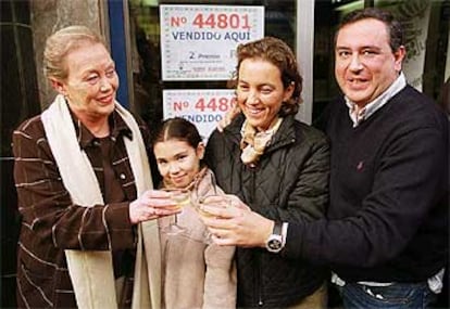 Esperanza Gállego, la lotera que repartió el segundo premio, brinda a la puerta de su establecimiento.